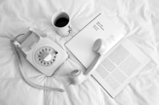 white rotary phone beside white ceramic mug