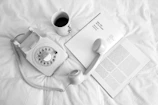 white rotary phone beside white ceramic mug