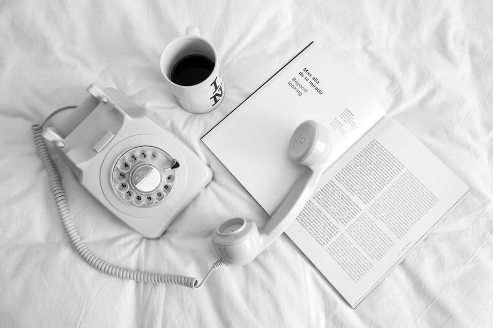 white rotary phone beside white ceramic mug