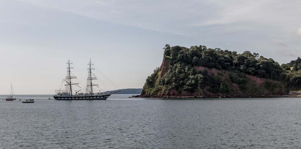 black ship on sea near green trees during daytime