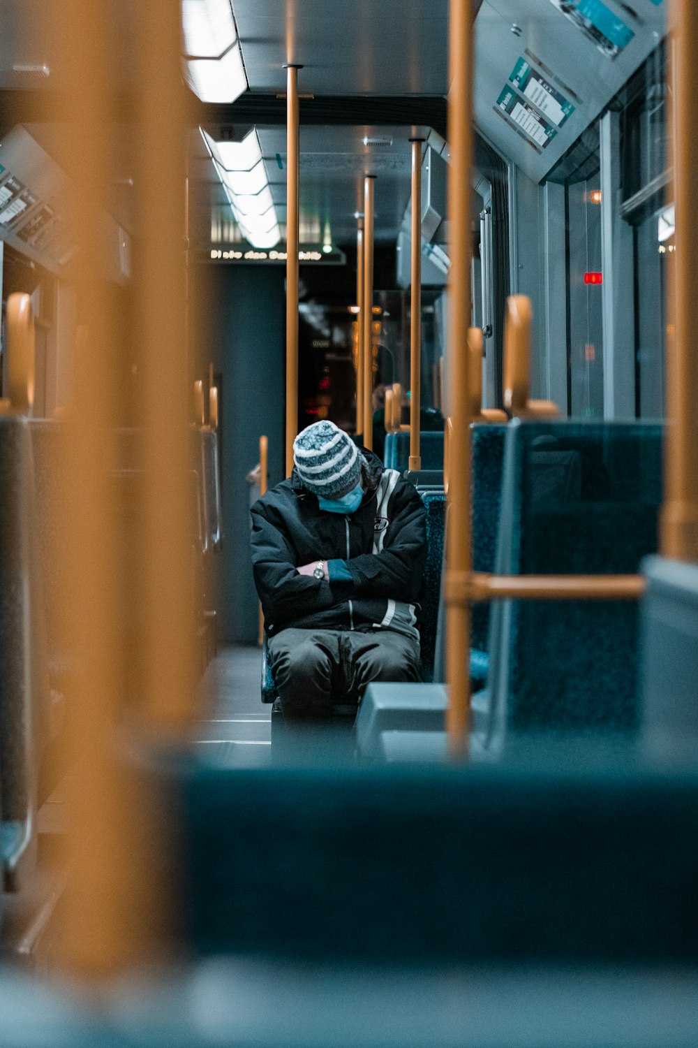 man in black jacket sitting on blue bench