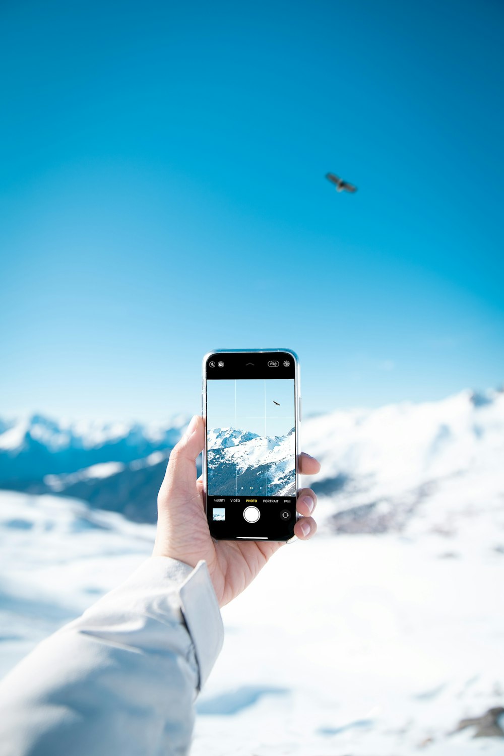 pessoa tirando foto da montanha coberta de neve durante o dia