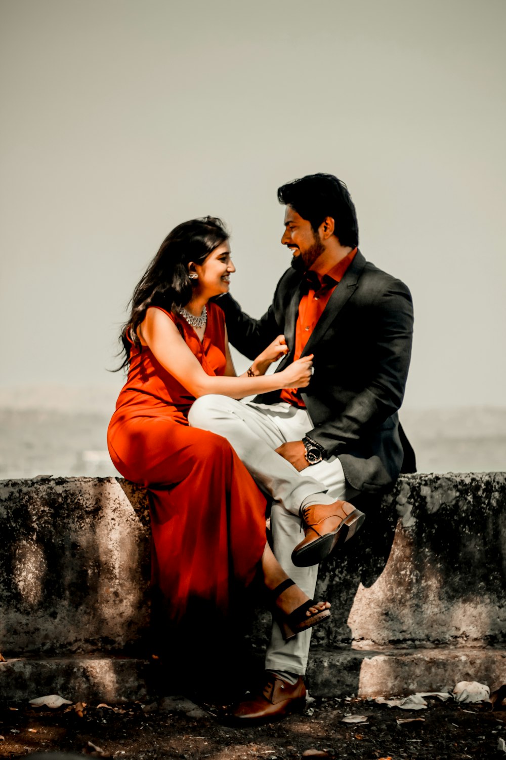 man and woman sitting on rock during daytime