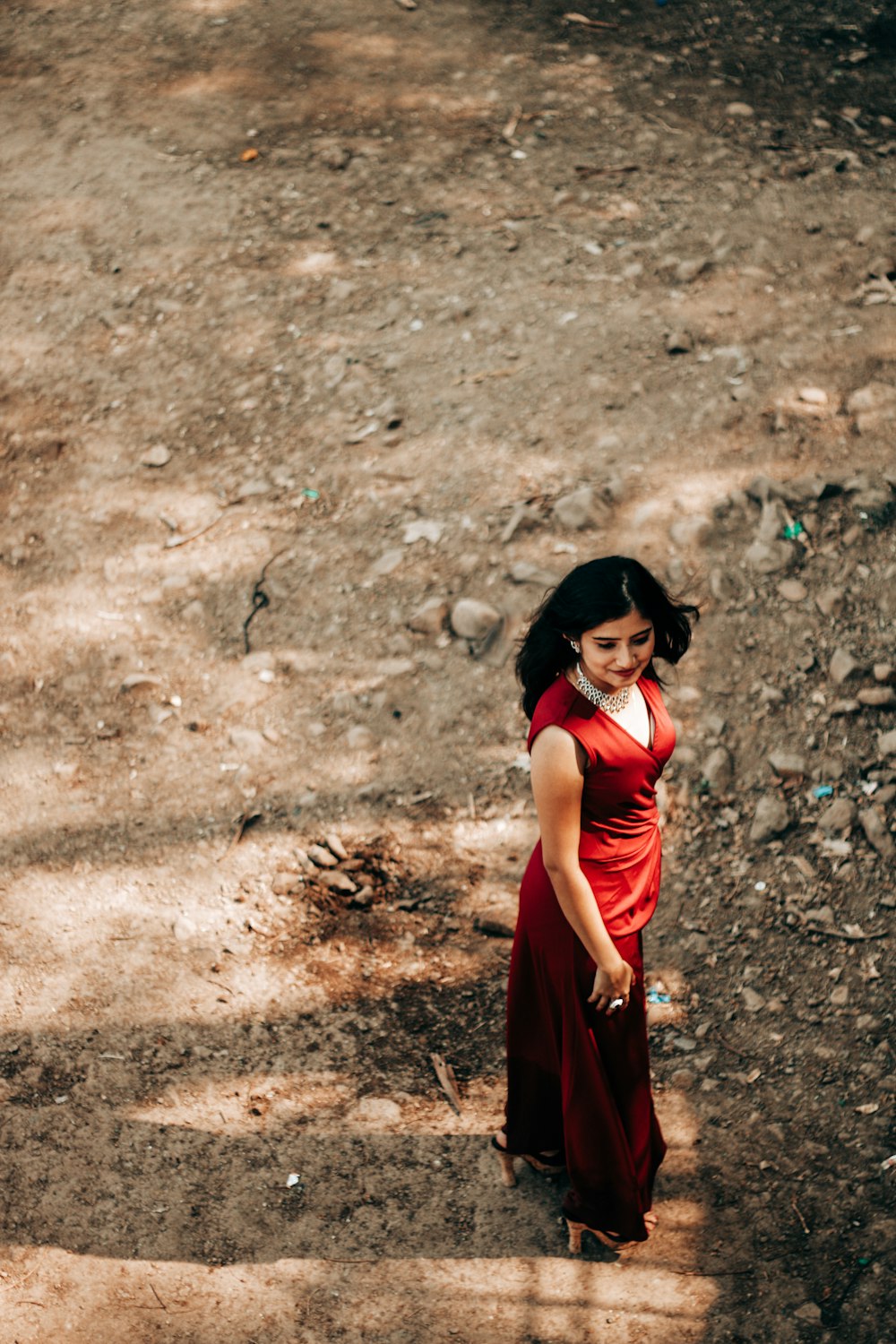 woman in red sleeveless dress standing on brown soil during daytime