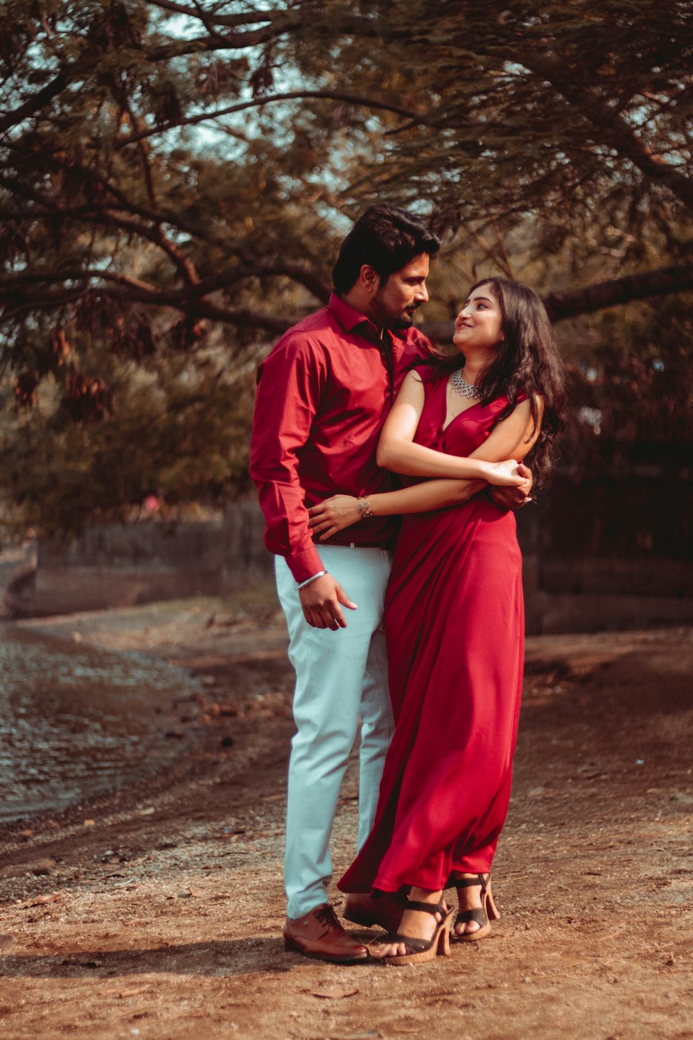 man in red long sleeve shirt hugging woman in red dress