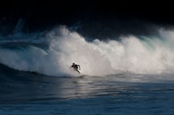 A surfer skillfully rides a large, crashing wave with water splashing around, conveying a sense of motion and adventure.