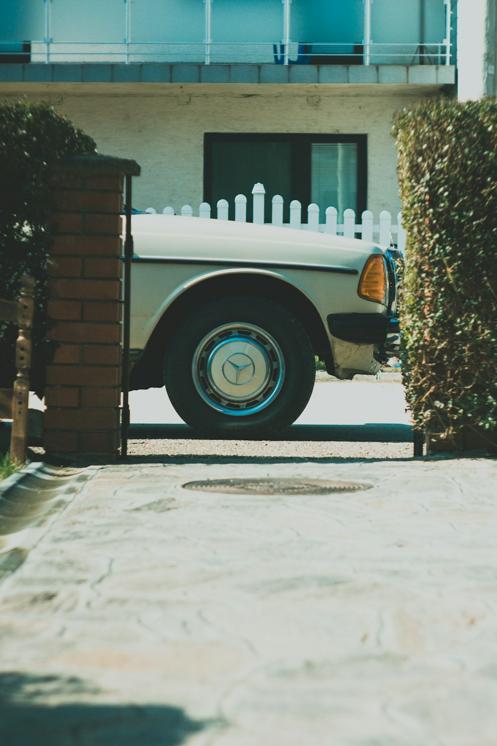 white car parked beside brown brick wall