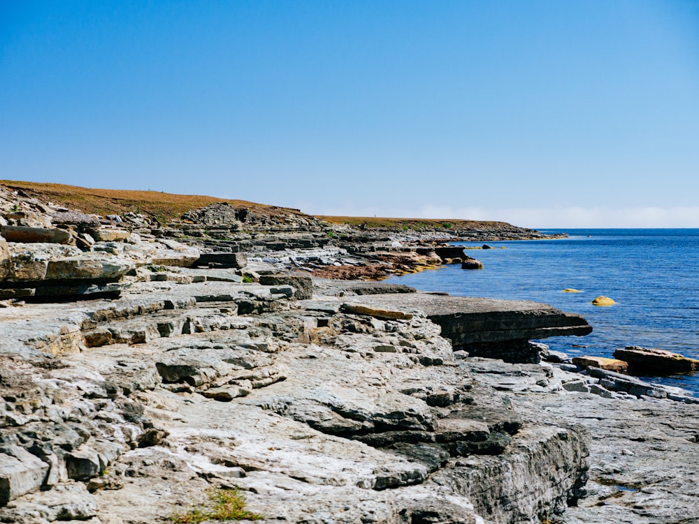 gray rocky shore near blue sea under blue sky during daytime