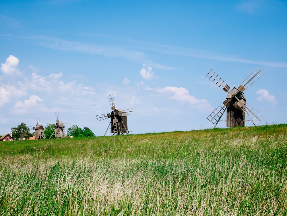 moinho de vento de madeira marrom no campo de grama verde sob o céu azul durante o dia