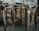 A row of freshly caught fish hanging from hooks on a metal rod. Each fish varies in size and type, with scales and fins clearly visible. In the background, snow can be seen, indicating a cold environment, along with a glimpse of a parked vehicle.