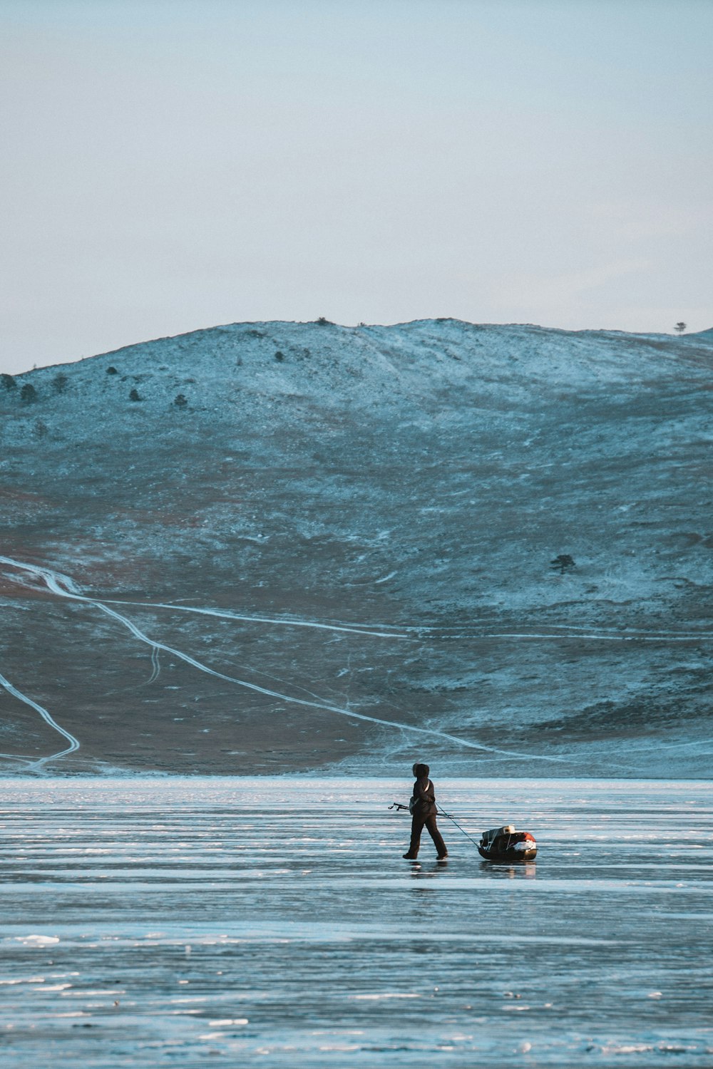 昼間、山の近くの雪原を歩く2人