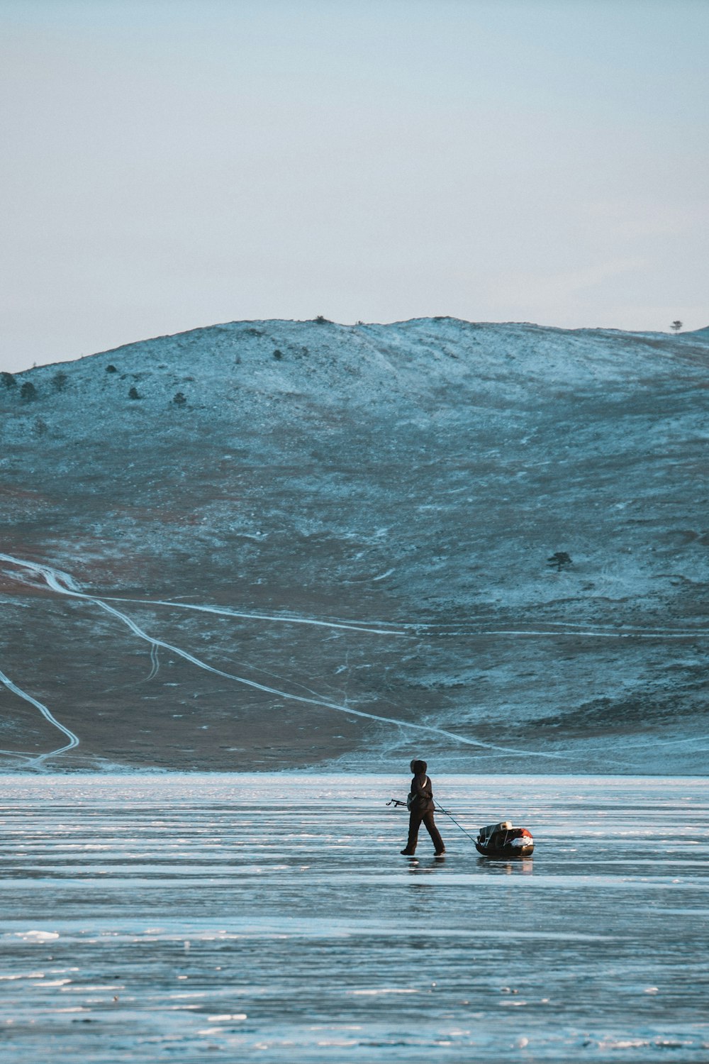 2 person walking on snow covered field near mountain during daytime