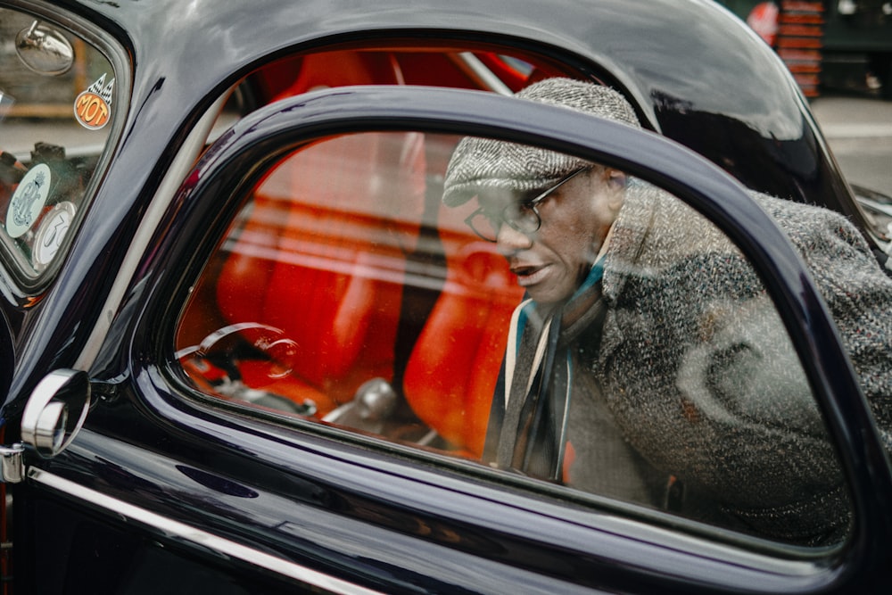 woman in red coat and black knit cap in car window