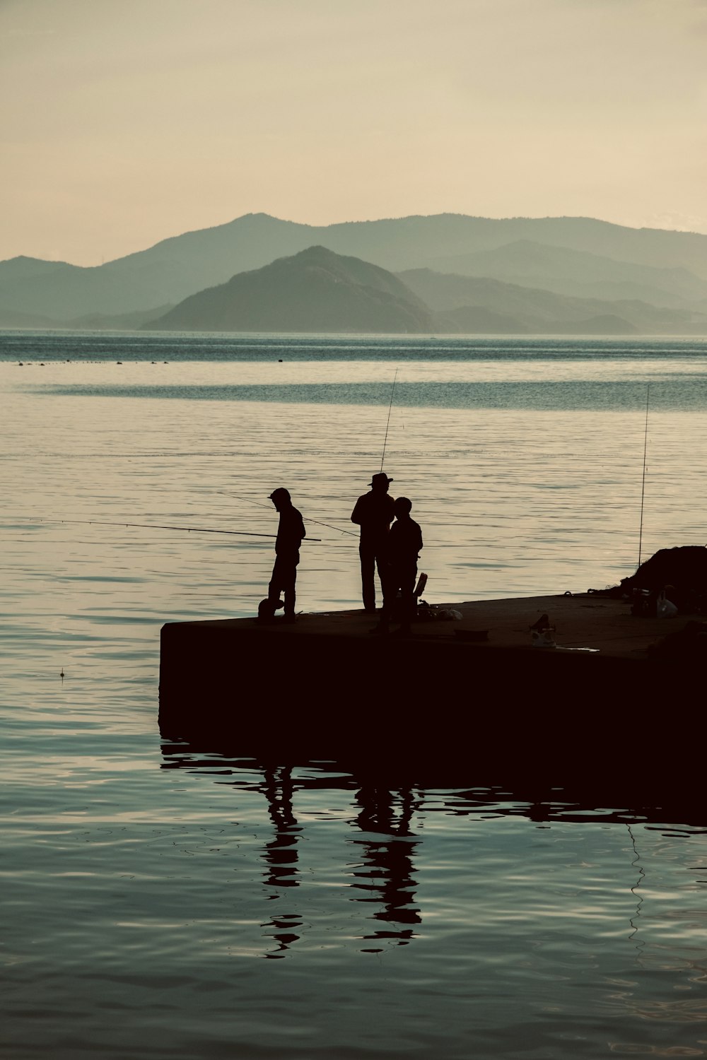 2 person standing on the edge of a boat in the sea during daytime