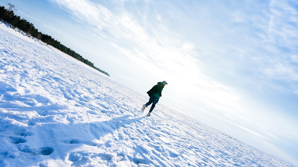 person in green jacket and black pants walking on snow covered ground during daytime