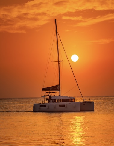 white sail boat on sea during sunset