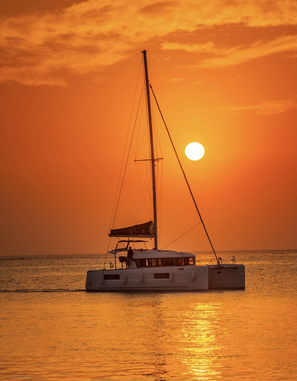 white sail boat on sea during sunset