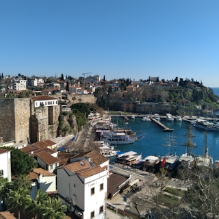 A picturesque Mediterranean harbor with multiple yachts and boats moored.