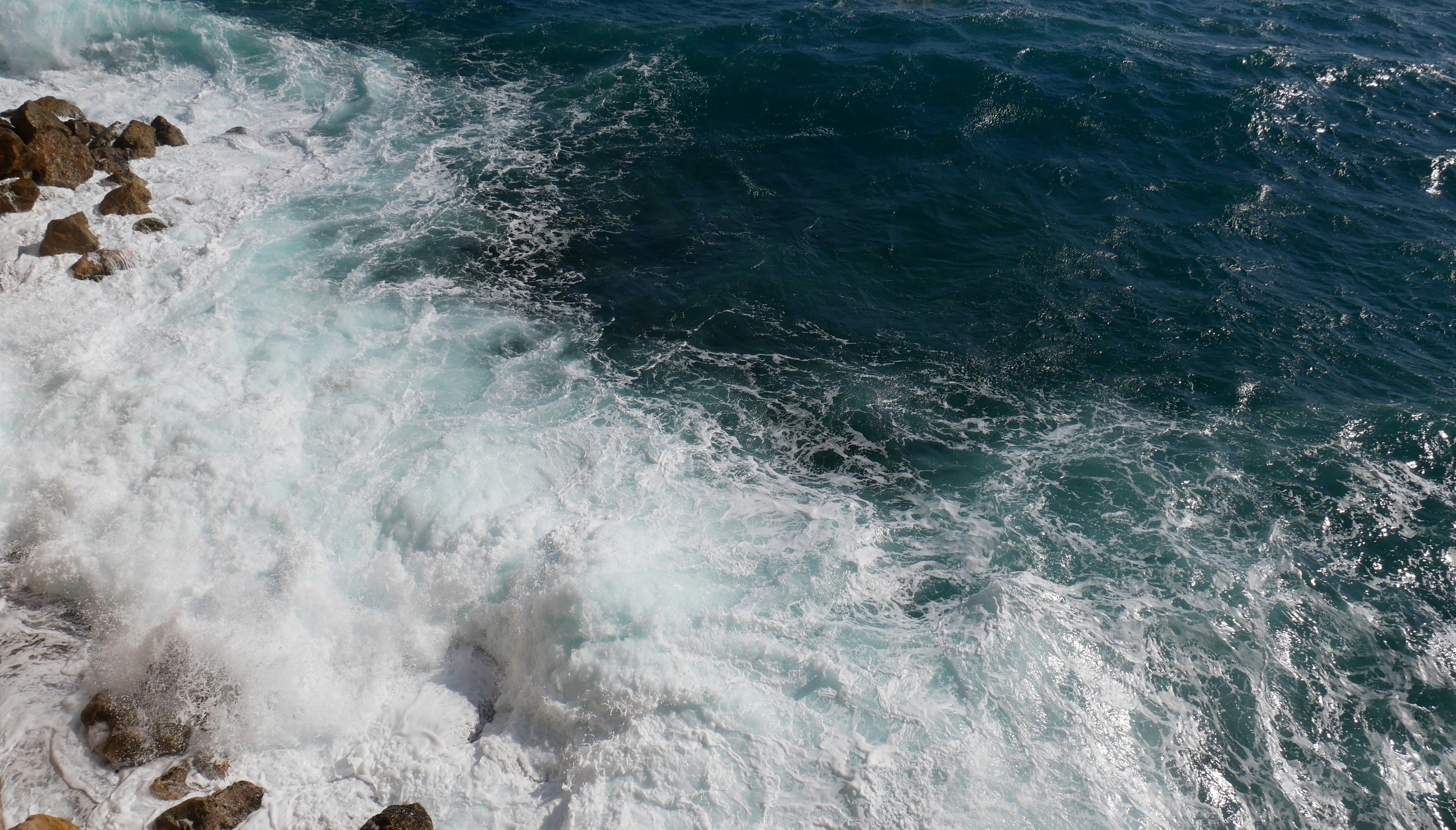 ocean waves crashing on rocky shore during daytime