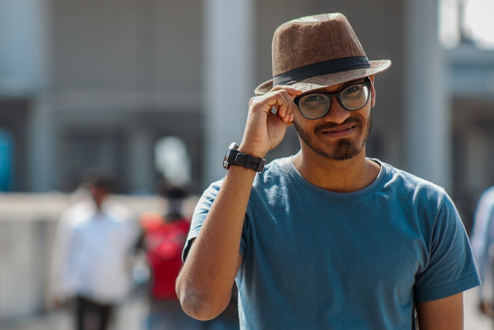 man in blue crew neck t-shirt wearing brown fedora hat