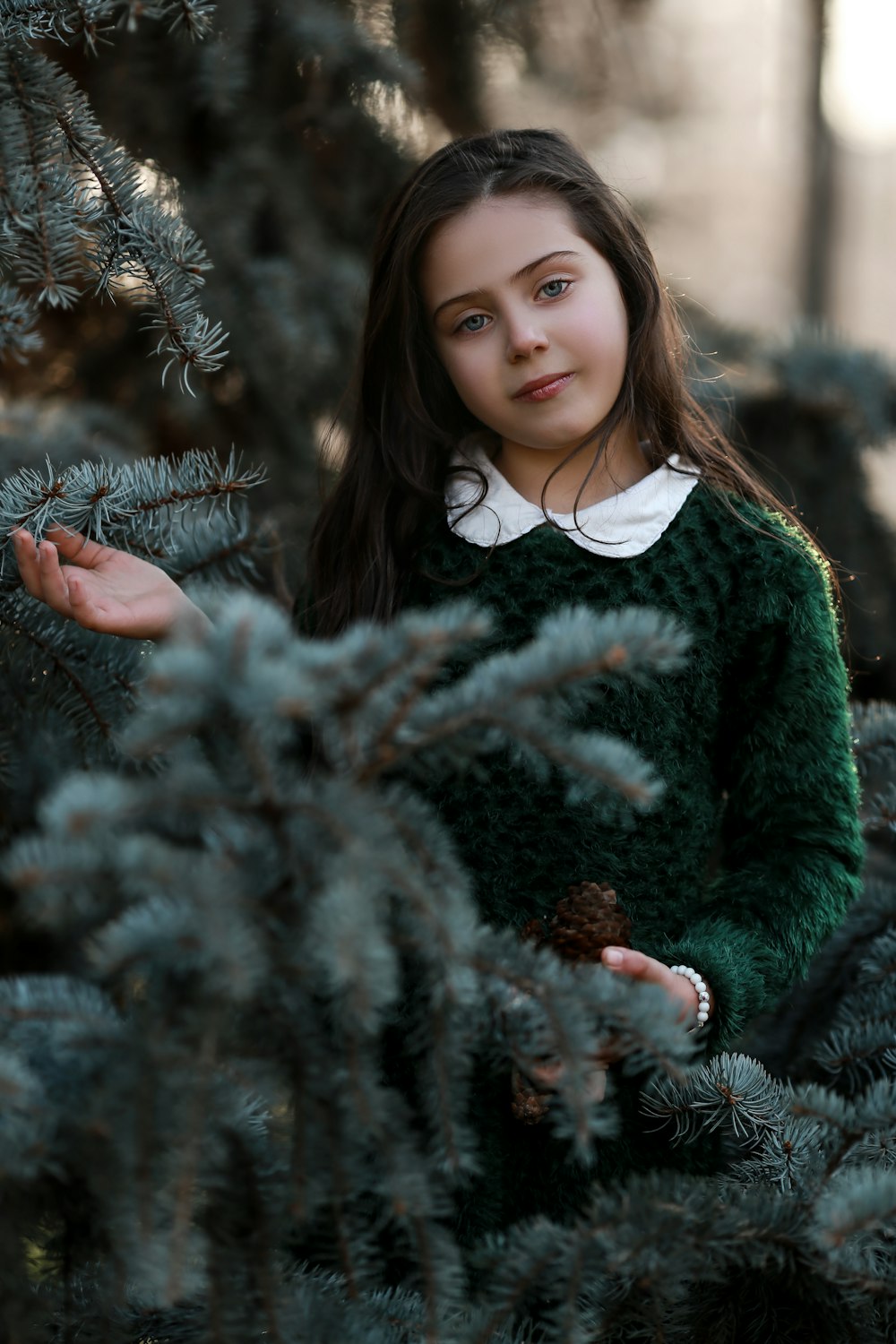 girl in green and white sweater holding brown plant