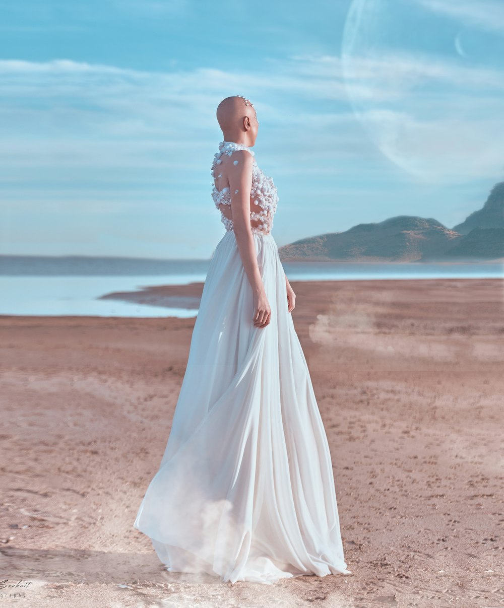 woman in white wedding dress standing on brown sand during daytime