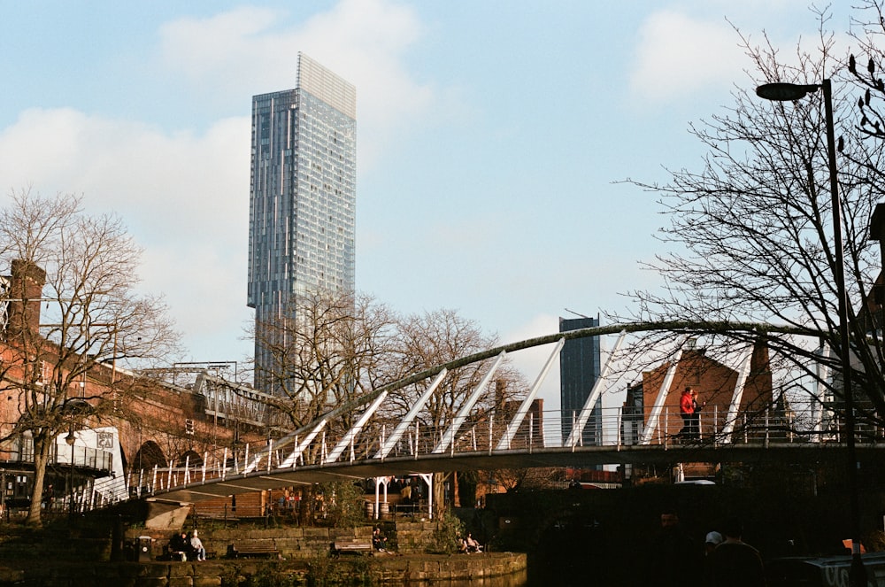 people walking on bridge near high rise buildings during daytime