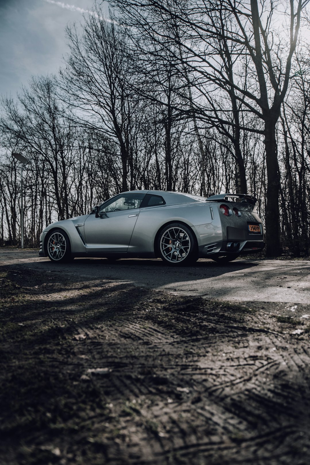 silver porsche 911 parked on dirt road near bare trees during daytime