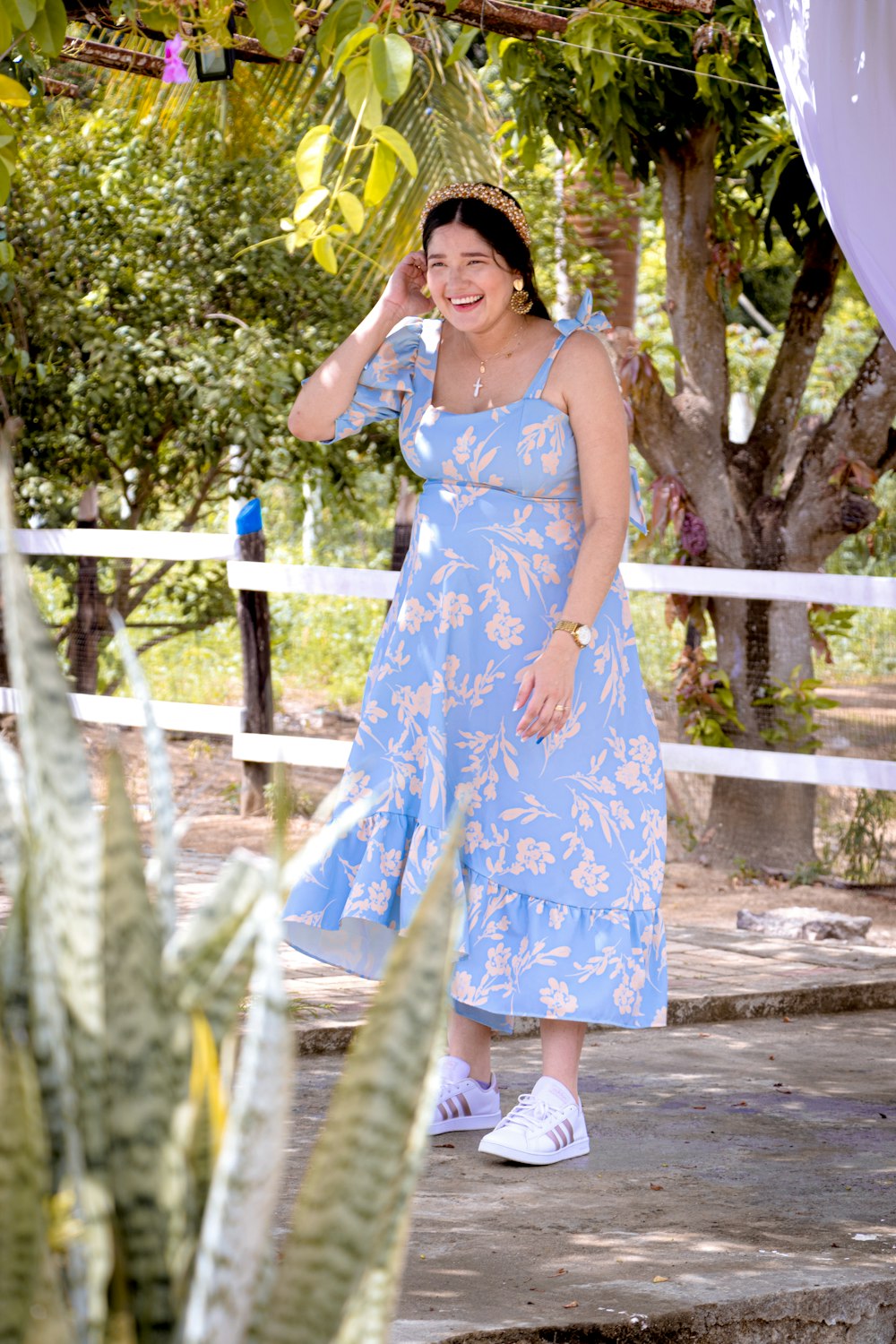 woman in blue and white floral sleeveless dress standing on wooden bridge during daytime