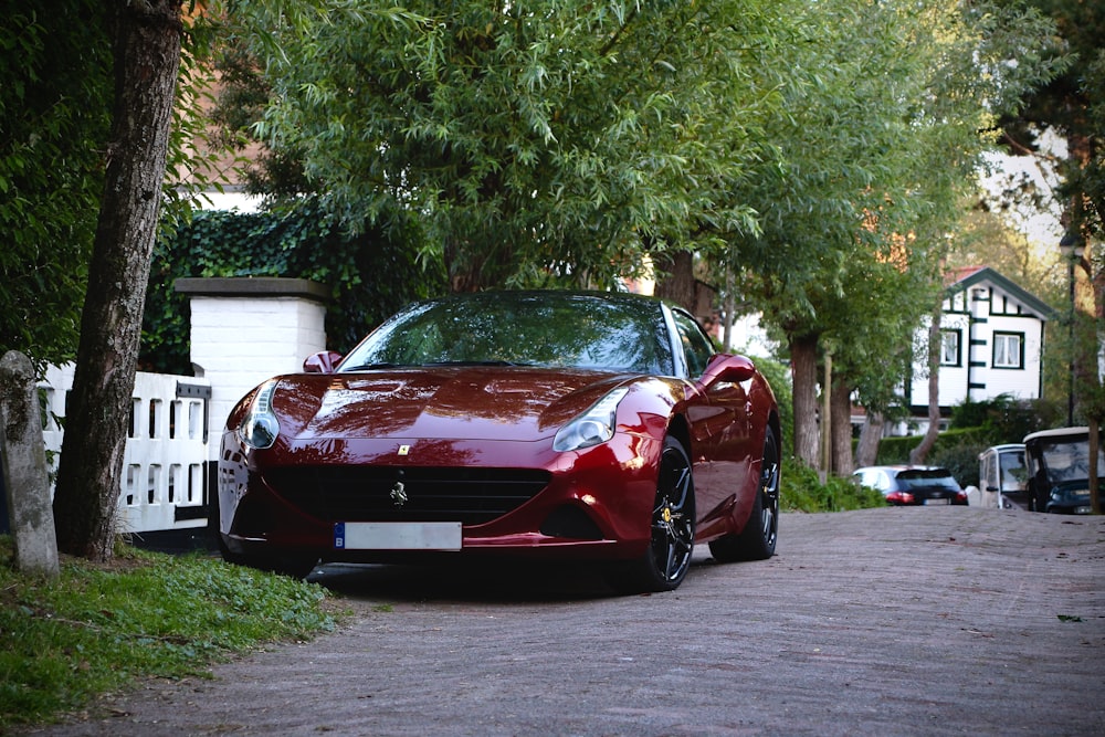 red ferrari 458 italia parked near green tree during daytime