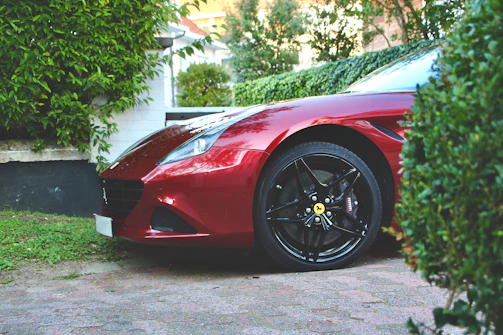 A sparkling red sports car parked on a driveway after a full mobile car wash and detail.