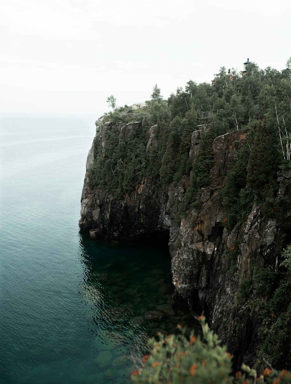 brown and green cliff beside body of water during daytime