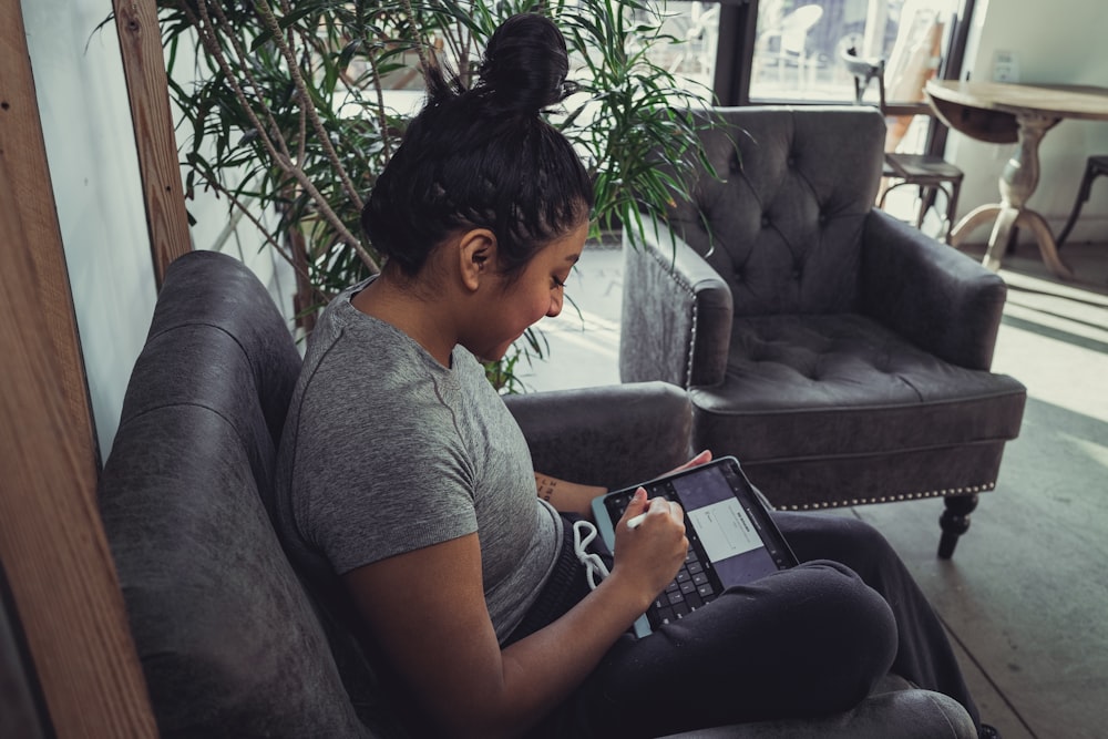 man in gray crew neck t-shirt and black pants sitting on gray couch