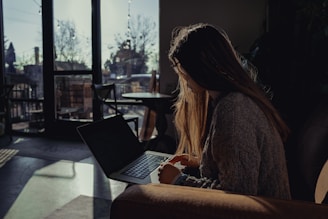 A guest relaxing with a laptop in a cozy hotel lounge, sunlight streaming through large windows.