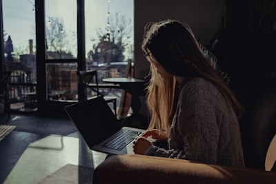 A guest relaxing with a laptop in a cozy hotel lounge, sunlight streaming through large windows.