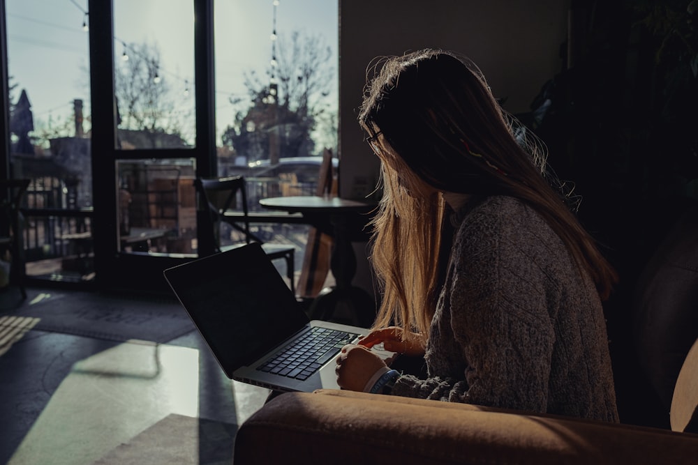 Frau im grauen Pullover mit Laptop