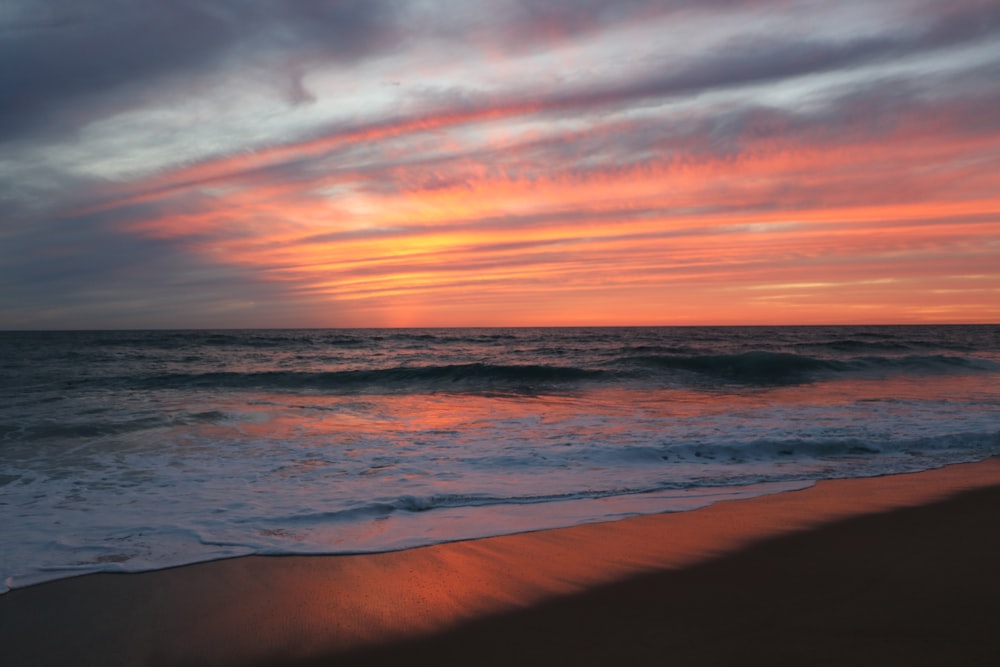 ocean waves crashing on shore during sunset