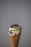 Close-up of a waffle cone filled with creamy vanilla ice cream topped with rainbow sprinkles.