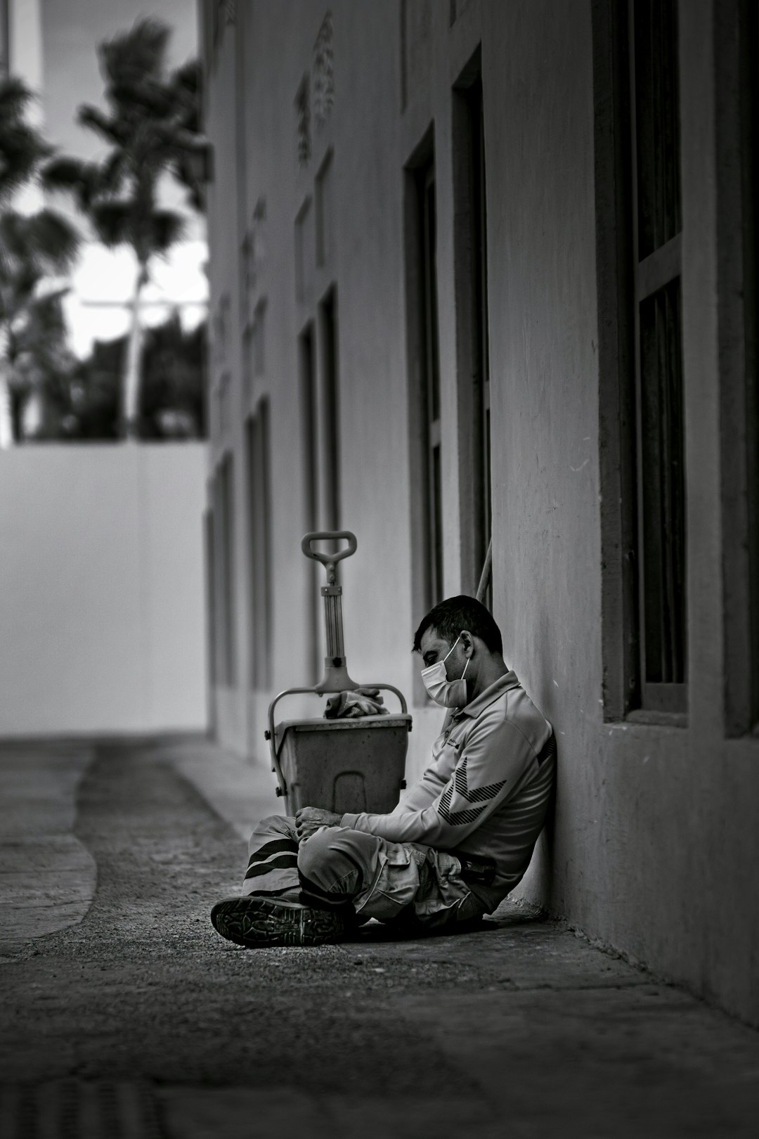 grayscale photo of man sitting on floor