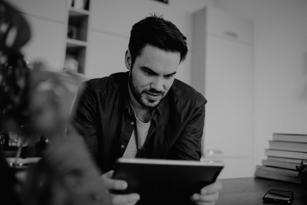 man in black suit jacket holding white tablet computer