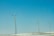 Three wind turbines stand on a snowy landscape under a clear blue sky. The turbines are evenly spaced, with long blades that are designed to capture wind energy.