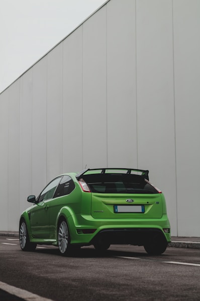 green chevrolet camaro parked beside white wall