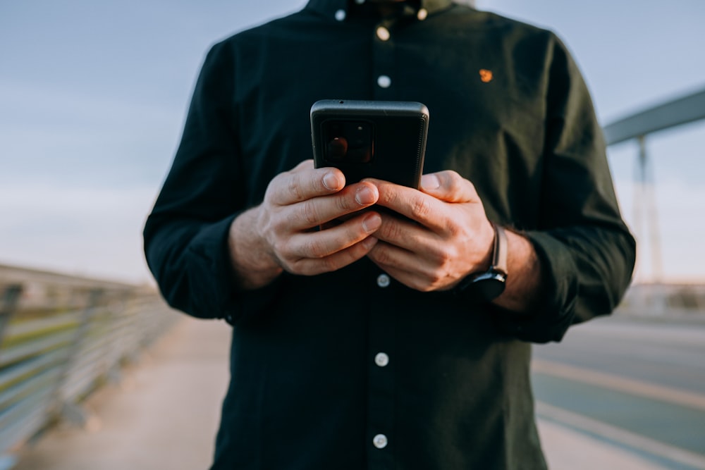 man in blue button up long sleeve shirt holding black iphone 5