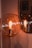 A warm, glowing light bulb encased in a spherical glass fixture, standing next to a reflective surface displaying its mirror image. The scene is captured in a soft, ambient lighting that enhances the bulb's filament details and creates a cozy atmosphere.