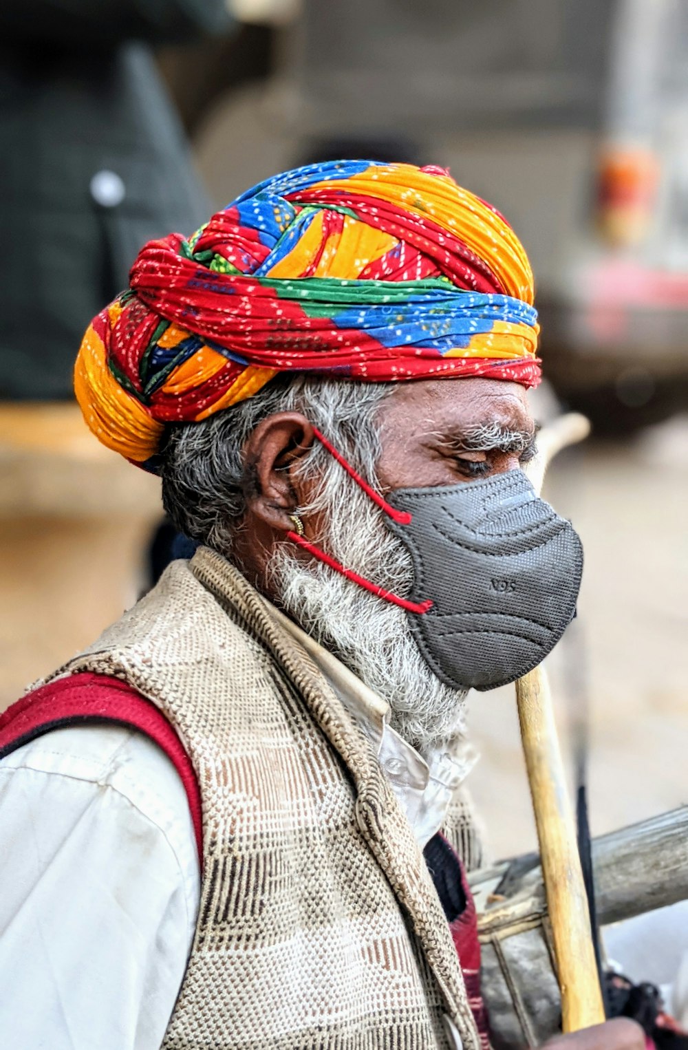 homme en chemise blanche et rouge portant un chapeau rouge, bleu et jaune