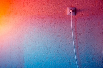 Electrician installing wiring in a modern home with blue and orange accents.
