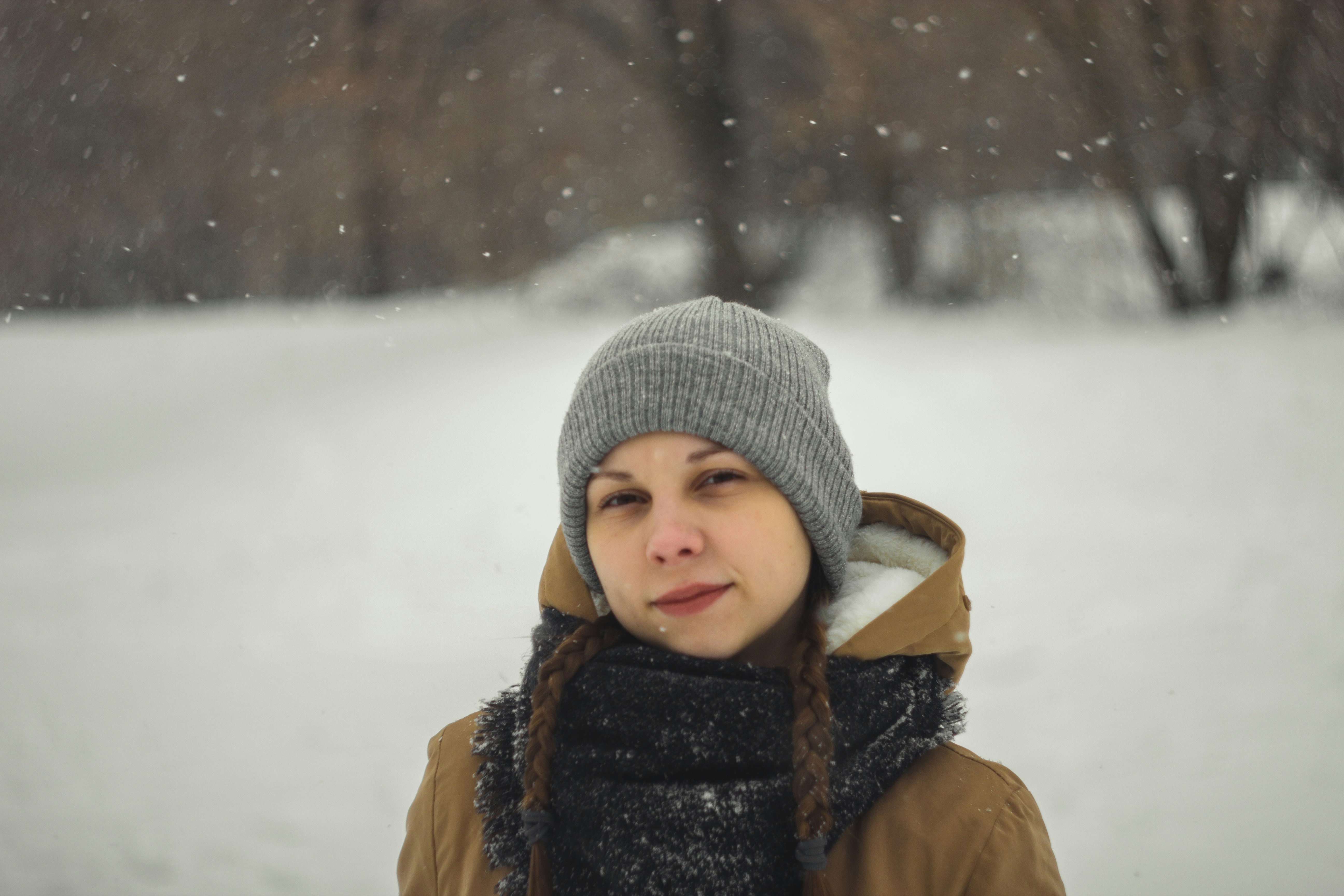 child in gray knit cap and brown jacket on snow covered ground during daytime