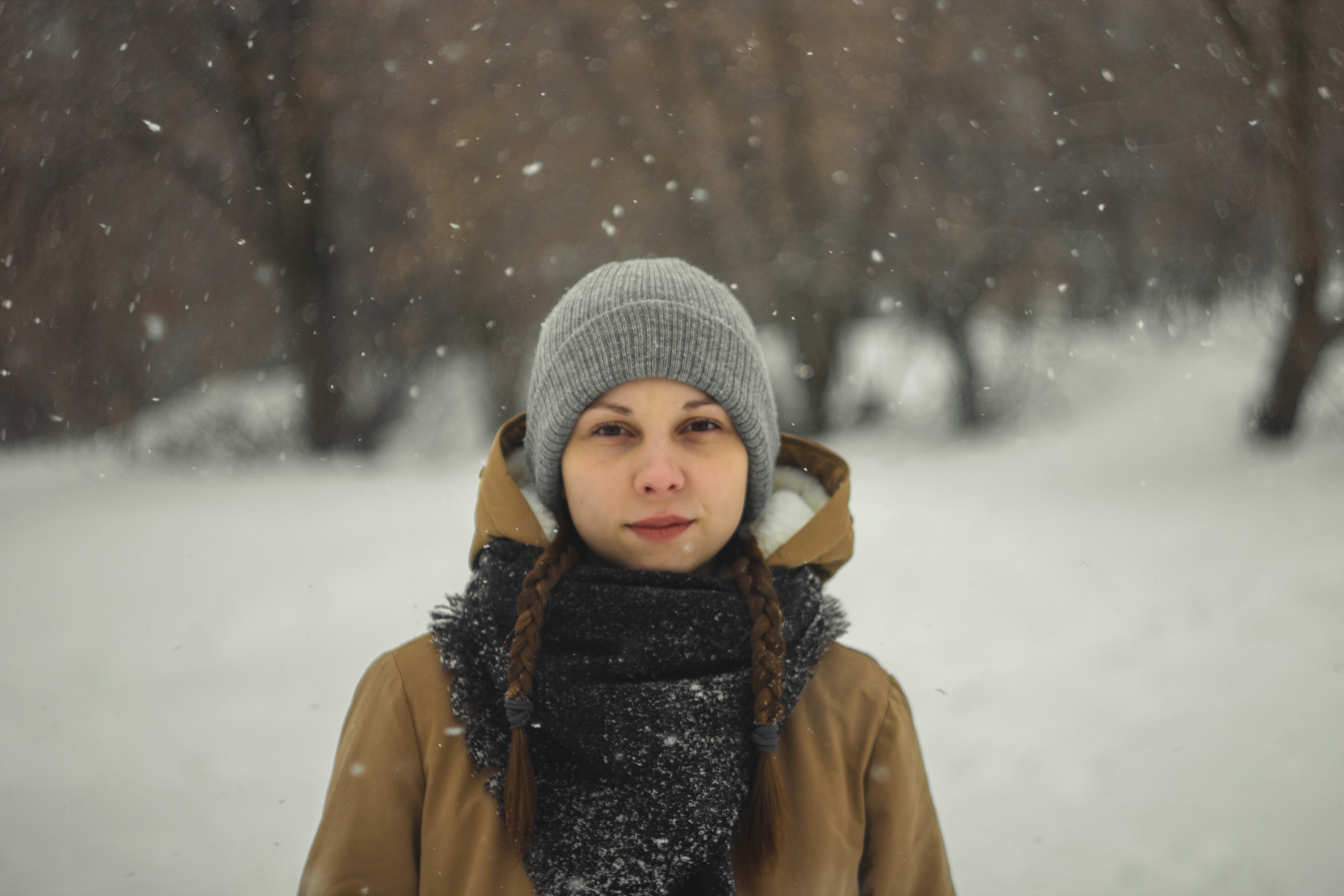 child in gray knit cap and brown coat on snow covered ground during daytime