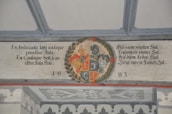 A detailed heraldic mural featuring a coat of arms situated in the center with intricate floral and scroll elements surrounding it. Latin and German text is inscribed on either side of the coat of arms, dated with the year 1683 beneath.