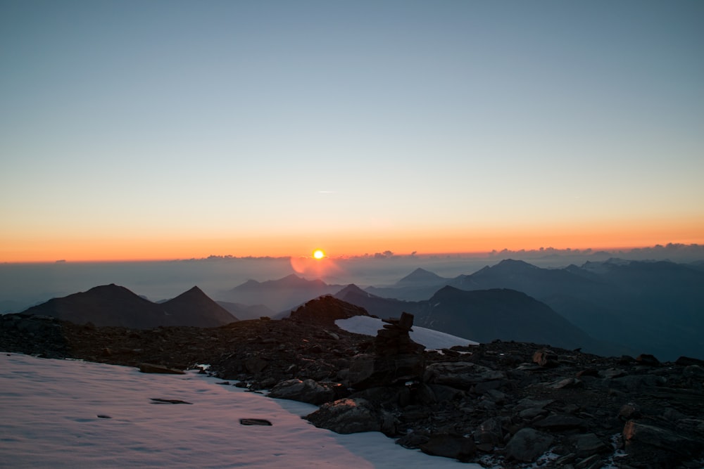 the sun is setting over a mountain range